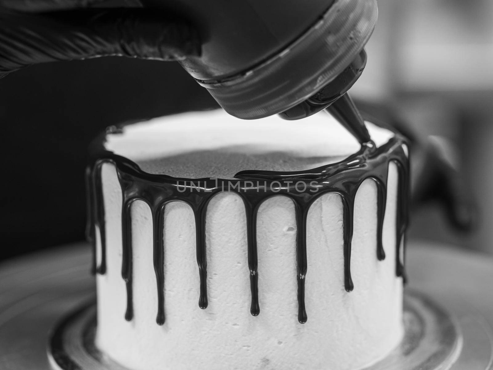 unrecognizable worker preparing a sweet dripping choco cake and berries