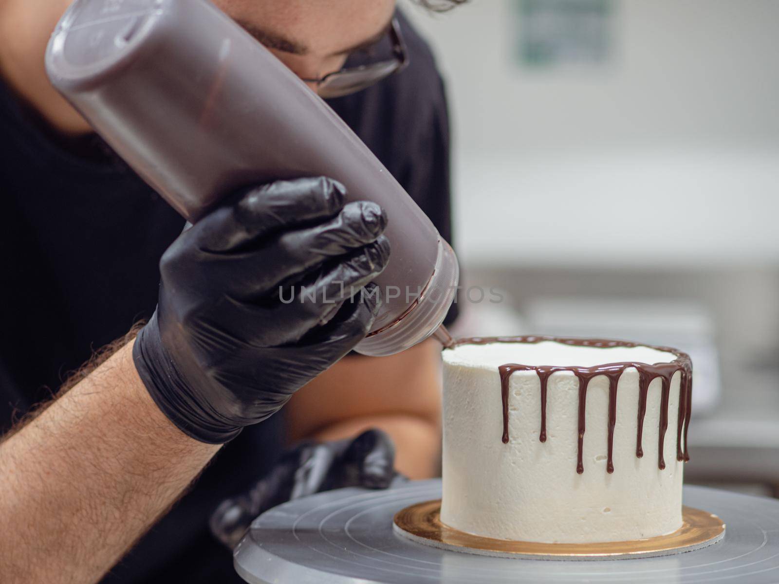 unrecognizable worker preparing a sweet dripping choco cake and berries