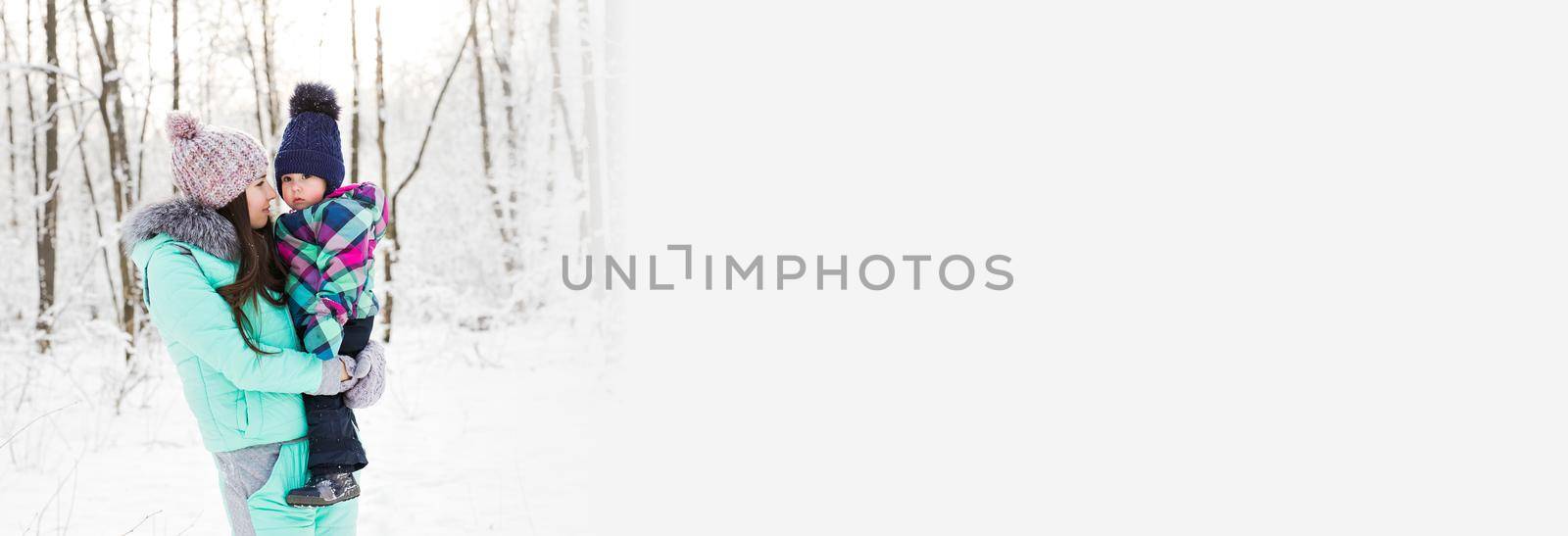 Banner happy family mother and child baby daughter on snow winter walk in woods copy space by Satura86