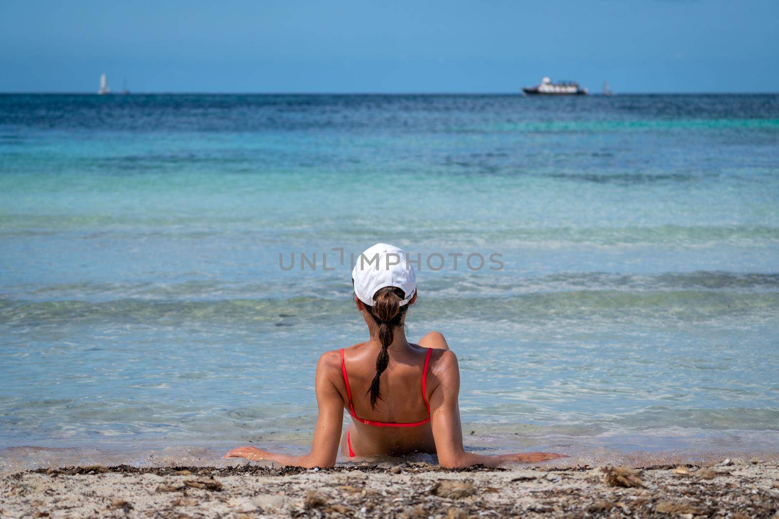 Brunette woman with coral bikini and cap posing on the beach