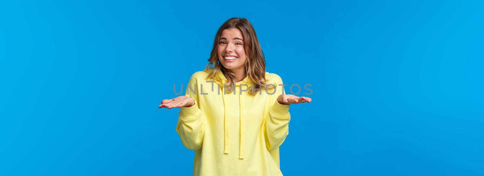 Oops sorry, no big deal. Carefree cute unbothered young blond girl making silly mistake and apologizing, say my bad shrugging and smiling embarassed, with awkward face, blue background by Benzoix