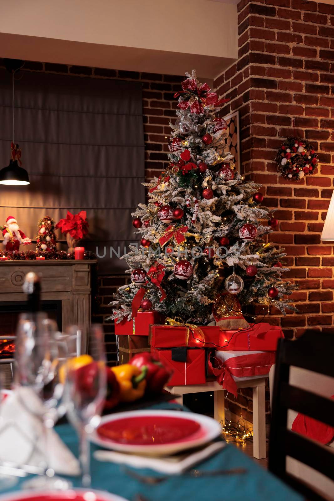 Decorated christmas tree, festive served table in luxury interior, winter seasonal holidays traditional preparations. Xmas presents under fir, garlands decor, warm candlelight in evening