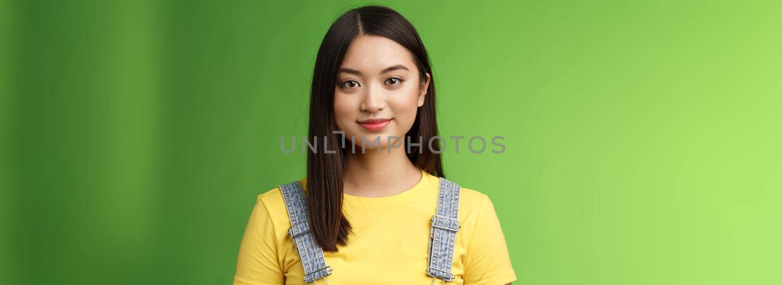 Waist-up friendly cheerful teenage asian college girl stand green background, smiling lovely, look tender amused, have relaxing casual conversation, packing things summer journey. Copy space