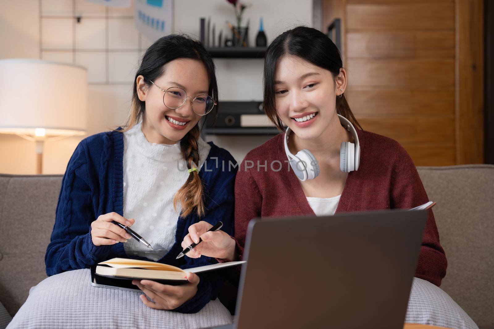 Two asian students learning together online with a laptop and tutor together at home.
