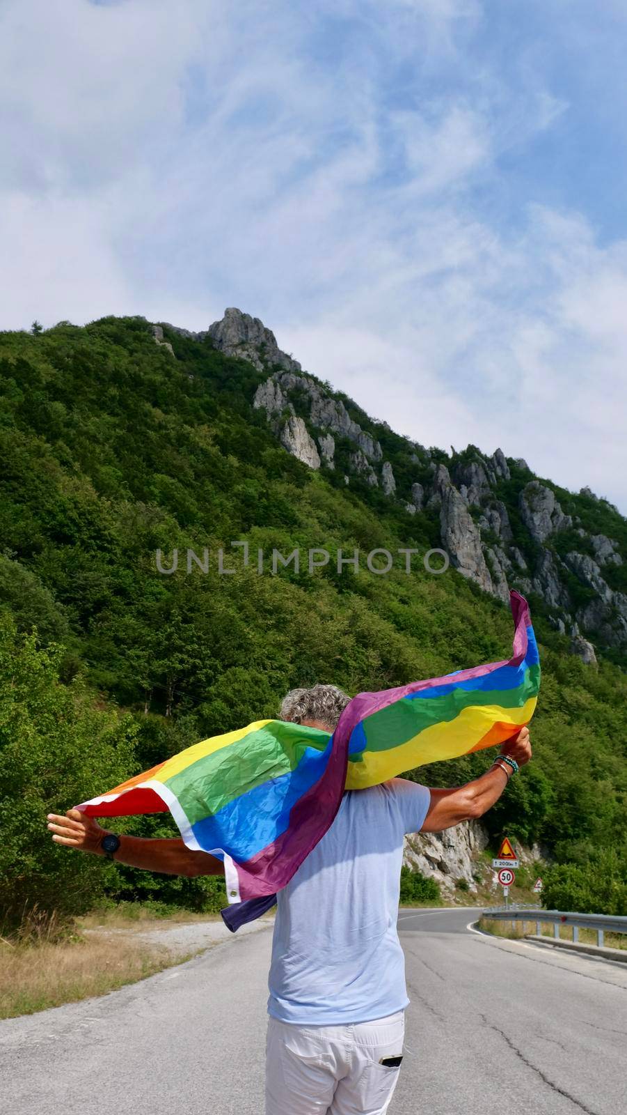 Bisexual, gay, old man, male, transgender walk back with LGBTQIA flag, rainbow peace in pride mounts on the nature on a day and celebrate Bisexuality Day or National Coming Out Day
