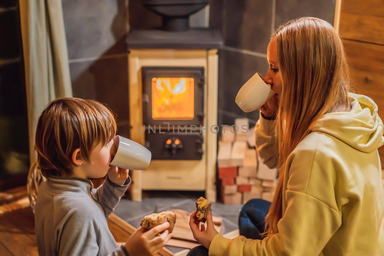 Mom and son spend time by the fireplace in Glamping. Rest in the mountains in Glamping. Cozy fireplace in a mountain house.