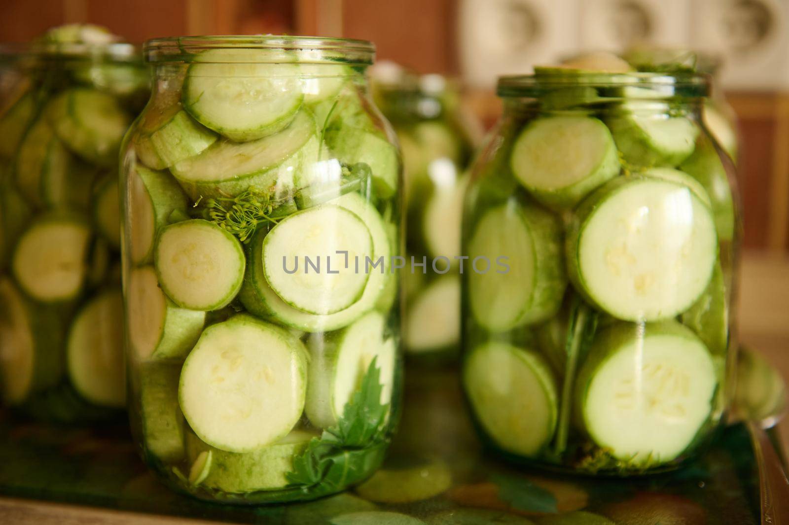 Slices of fresh organic courgettes, just marinated in a brine with seasoning and fresh dill in sterilized canning cans, for the winter. Making preserves. Canned vegetable marrows, zucchini.