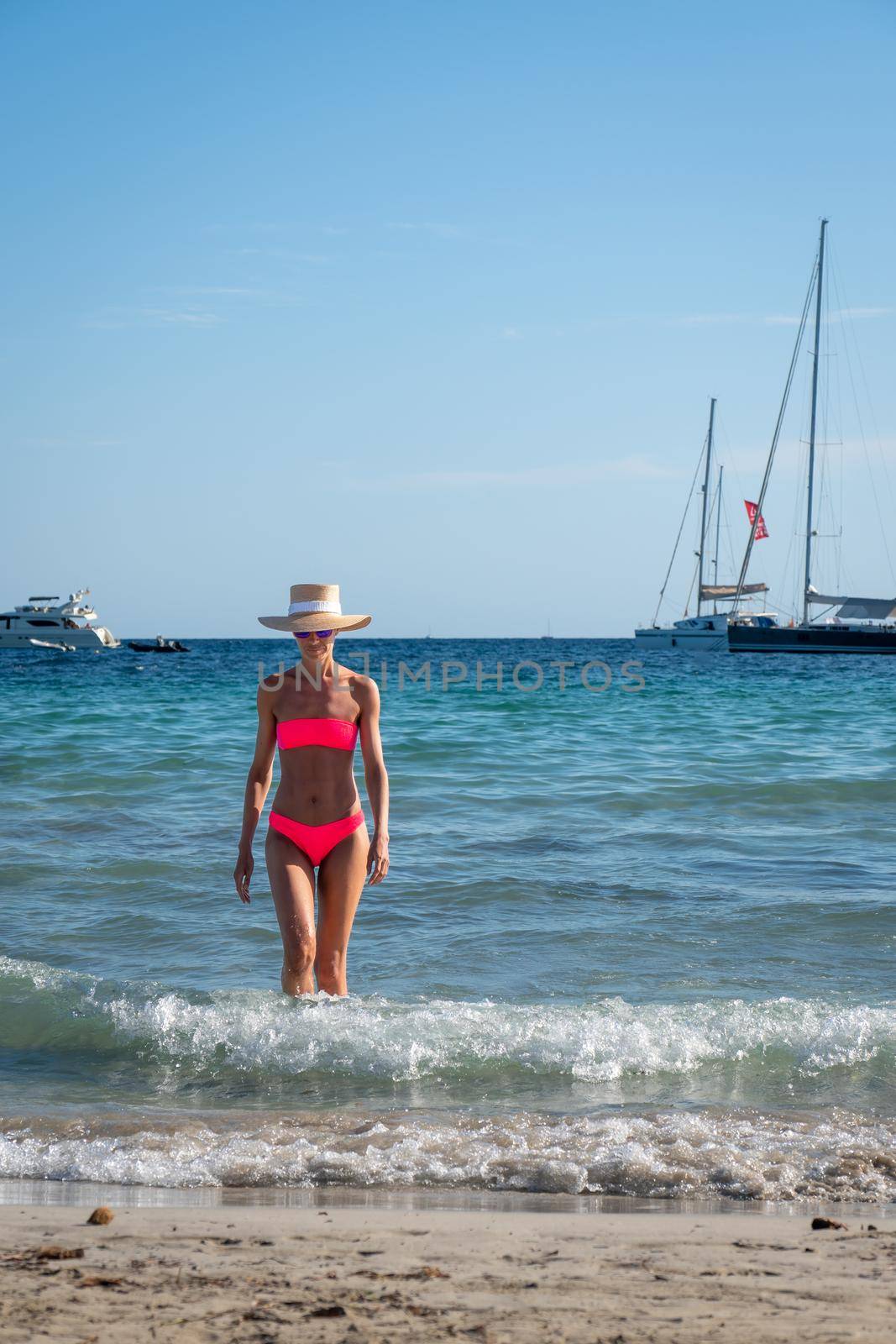 Brunette woman with pink bikini and hat coming out of the sea by LopezPastor