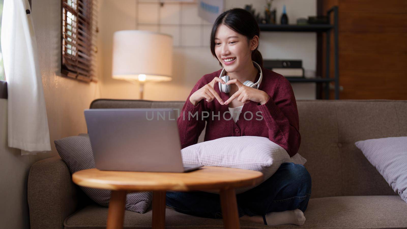Young asian woman sitting on couch looking at laptop in cozy living room at home. Lifestyle concept.