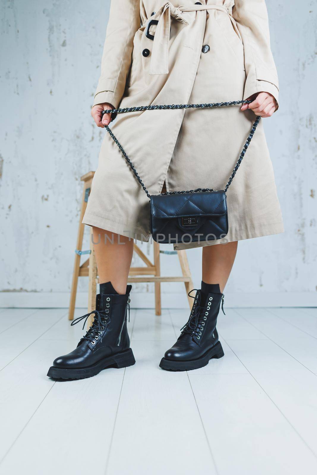 Close-up of female legs in black leather lace-up shoes. Black leather handbag in female hands. New autumn collection of women's leather shoes 2022