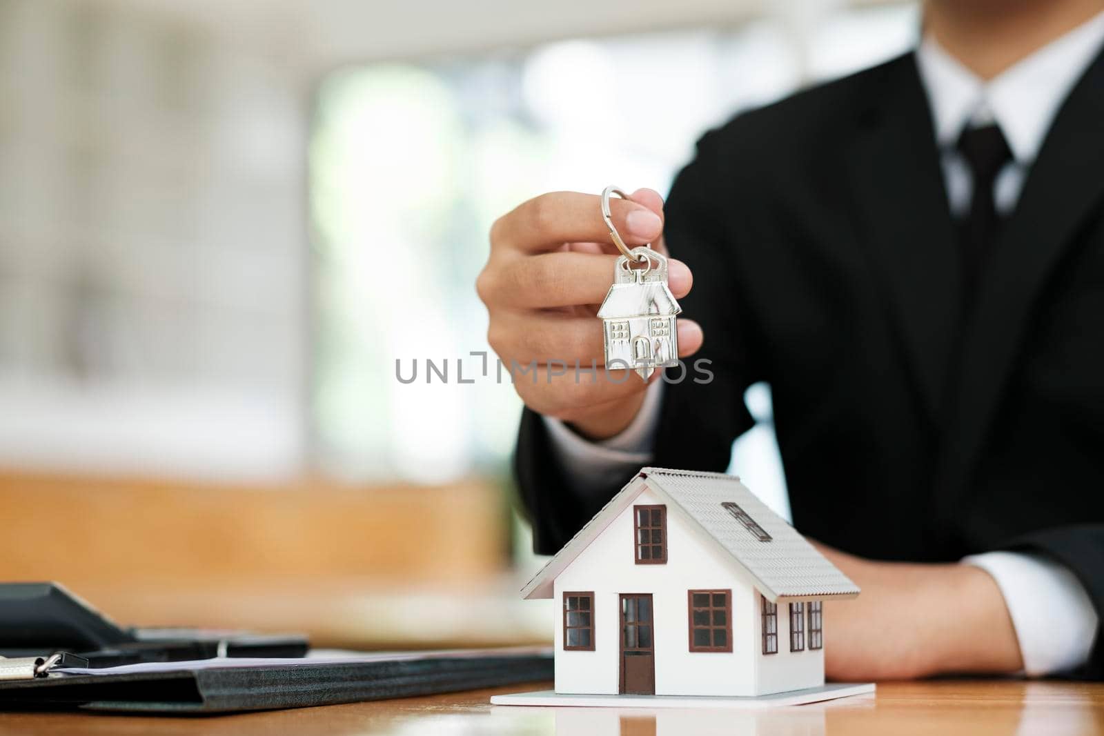 Real estate agent holding house model and keys to consult client. by ijeab