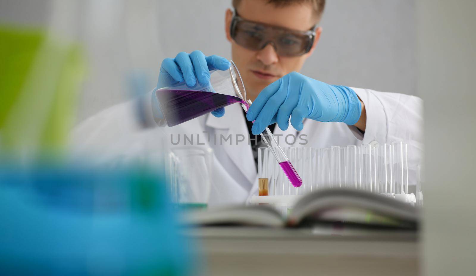 Scientist in protective gloves holding test tube of purple liquid. Laboratory research of poisonous liquids concept