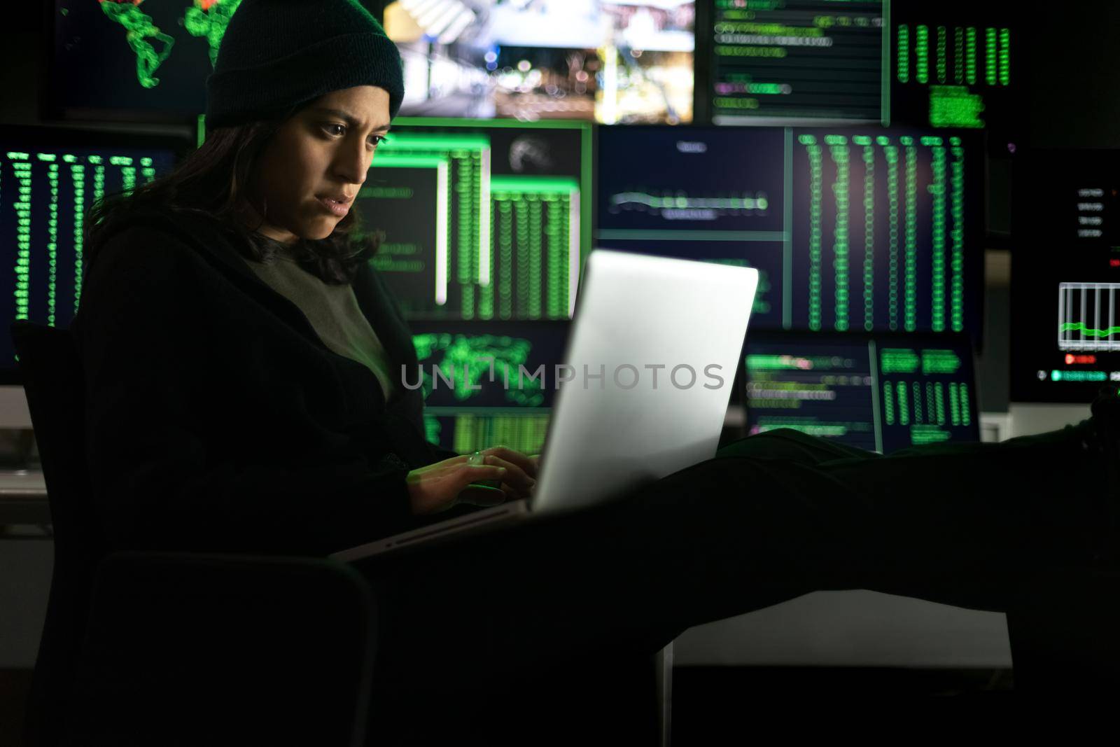 Latina female hacker using laptop to organize malware attack on global scale. Hacking concept.