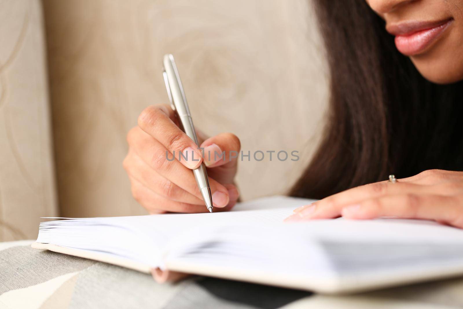 Closeup of hands of black female writer at home writing in magazine. Copywriter journalist and training concept