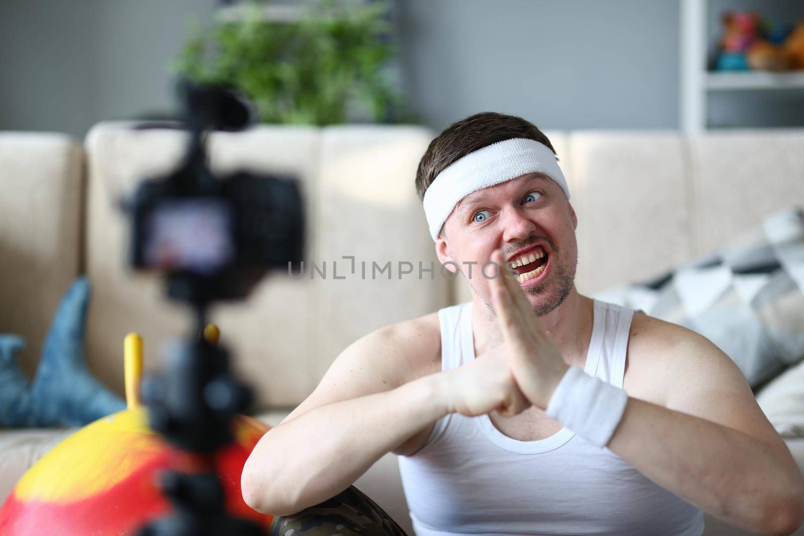 Male blogger makes gestures and fist in left palm in front of camera. Anger and sports motivation and purpose