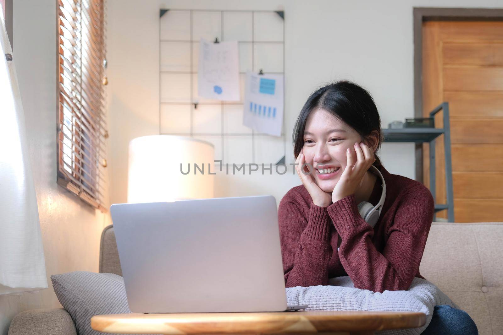 Asian woman are using notebook computers and wear headphones for online meetings and working from home. by wichayada