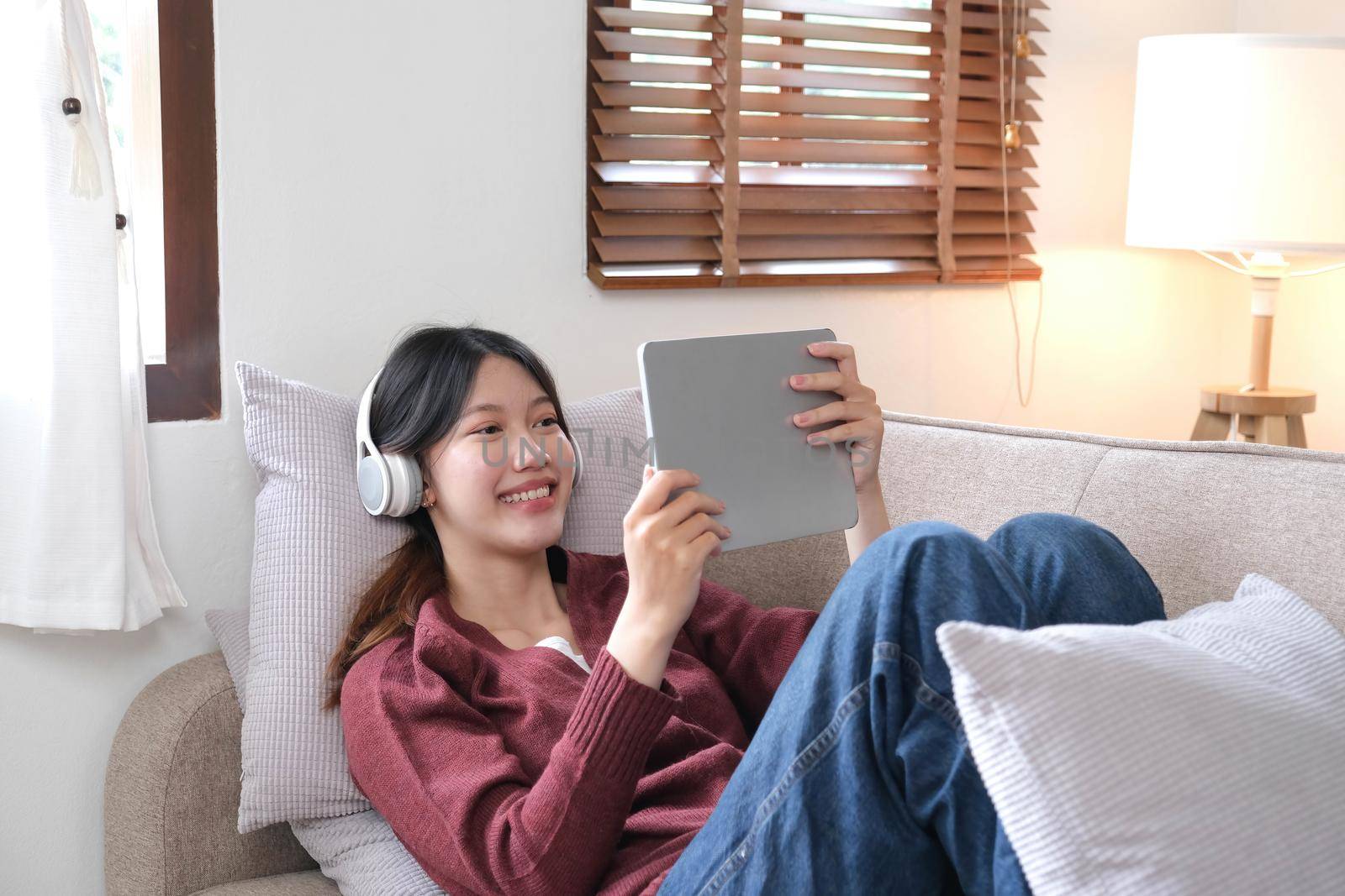 Attractive smiling young woman using tablet and listen music on sofa at home. lifestyle concept..