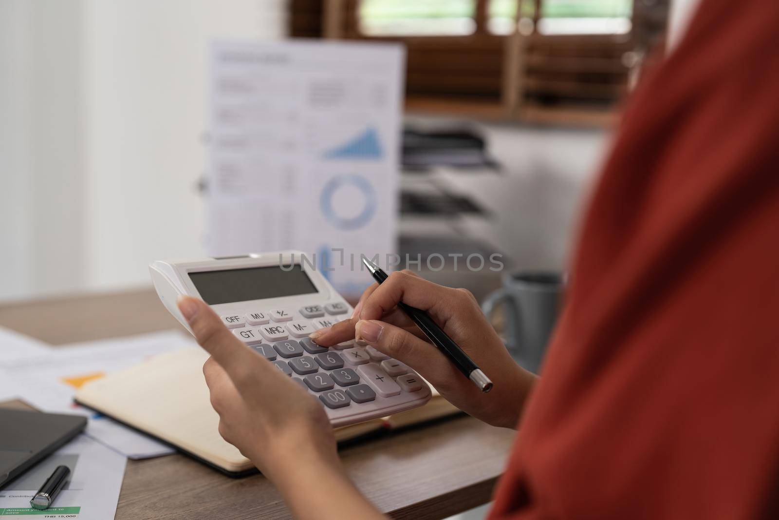 Business woman hand using calculator to calculate the financial results. work from home concept.