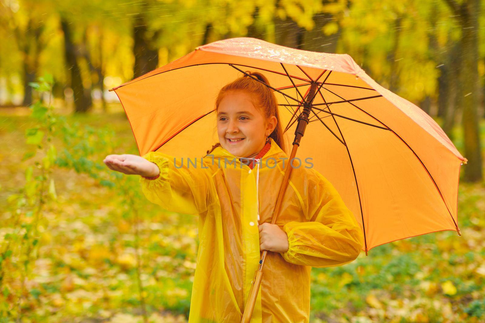 happy kid catching rain drops in Autumn park by InnaVlasova