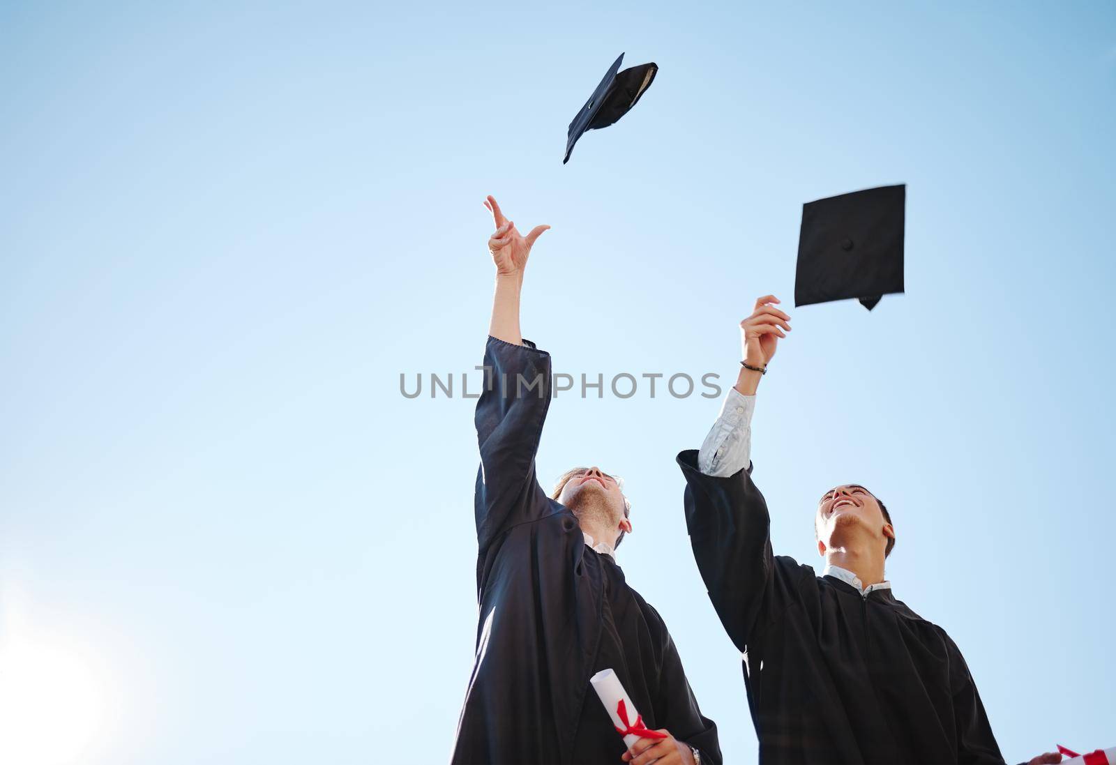 Graduation cap throw, blue sky and friends after a diploma, certificate and degree ceremony event. Education, university and school scholarship success of students happy about college achievement.