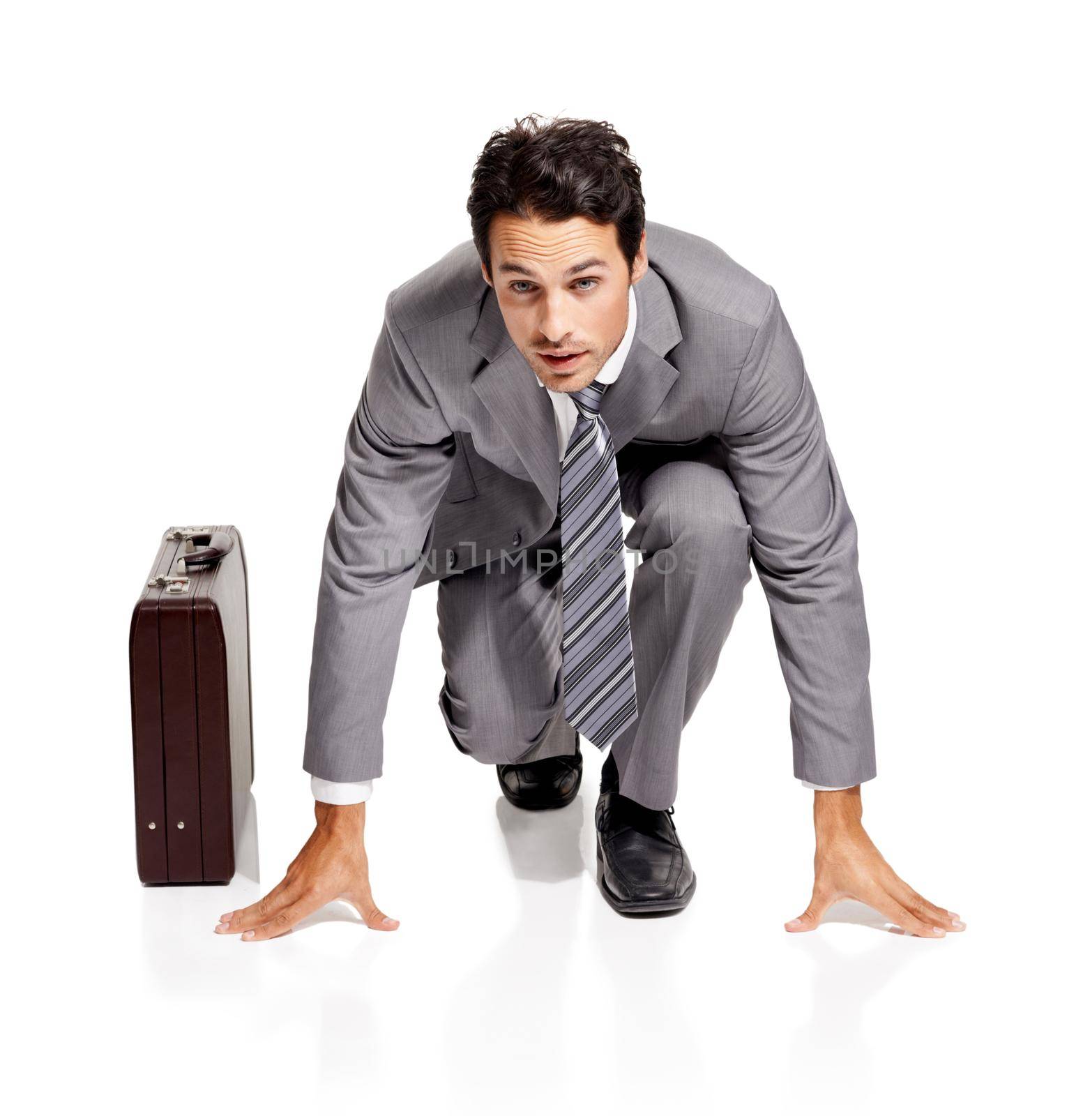 Ive gotto be ahead of the pack. A young businessman crouching in the starting position next to his briefcase