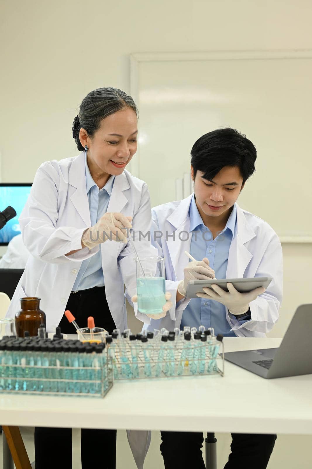 Professional scientists team conducting experiment in modern laboratory. Medicine and science researching concept by prathanchorruangsak