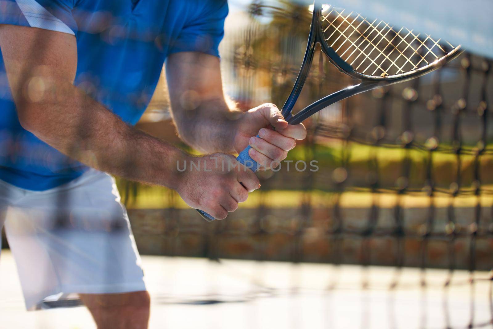 Getting to grips with tennis. Cropped image of a male tennis player holding his racquet seen through the tennis net. by YuriArcurs
