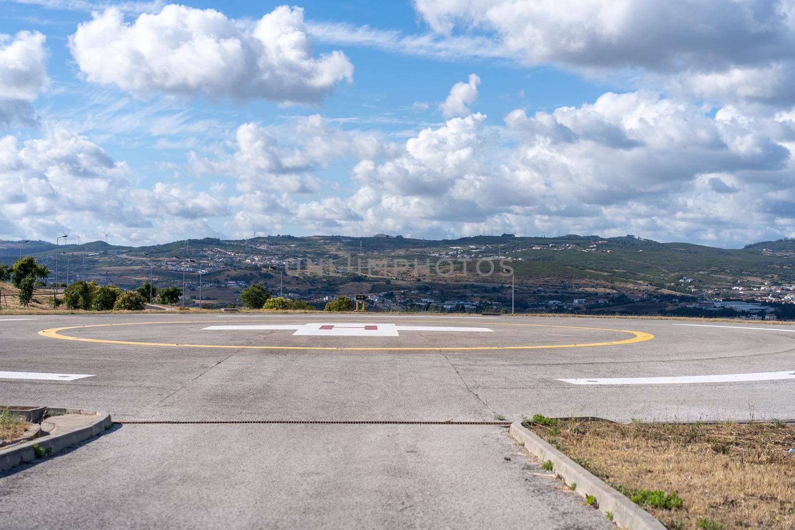 Helipad. Helicopter Landing Pad near emergency hospital in Portugal with cloud sky and city on background by andreonegin