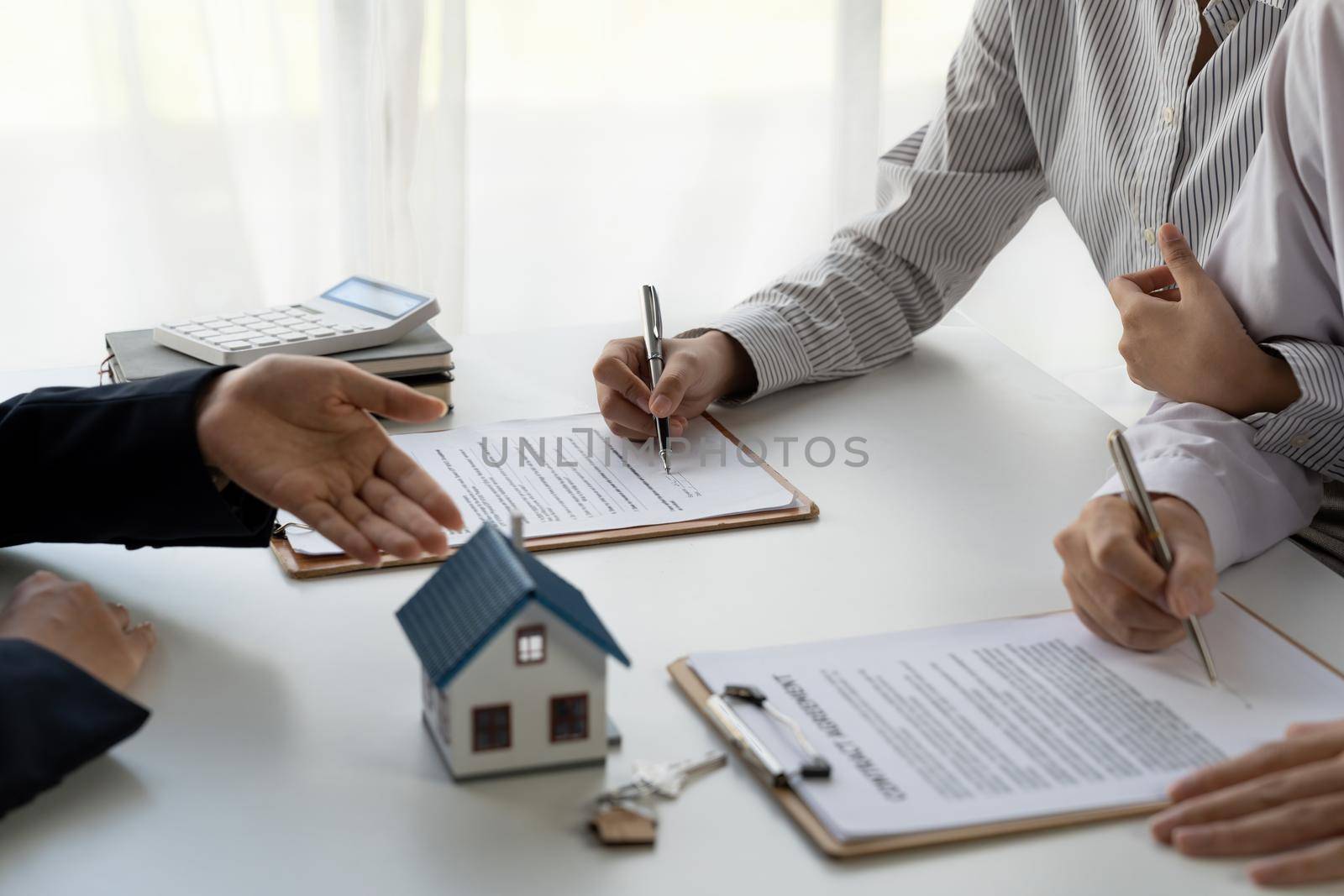 Real estate agent with couple closing a deal and signing a contract. by nateemee
