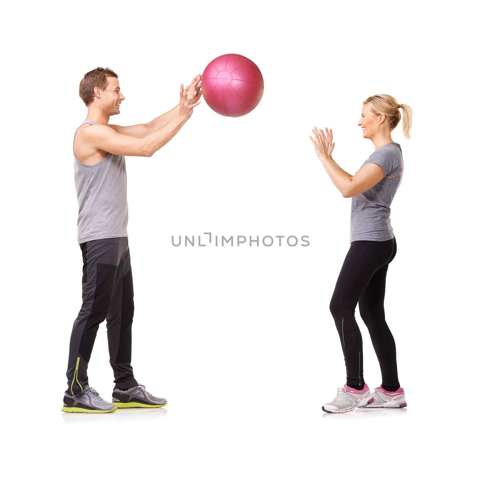 Getting fit is fun. A man and woman exercising by throwing a medicine ball to each other. by YuriArcurs