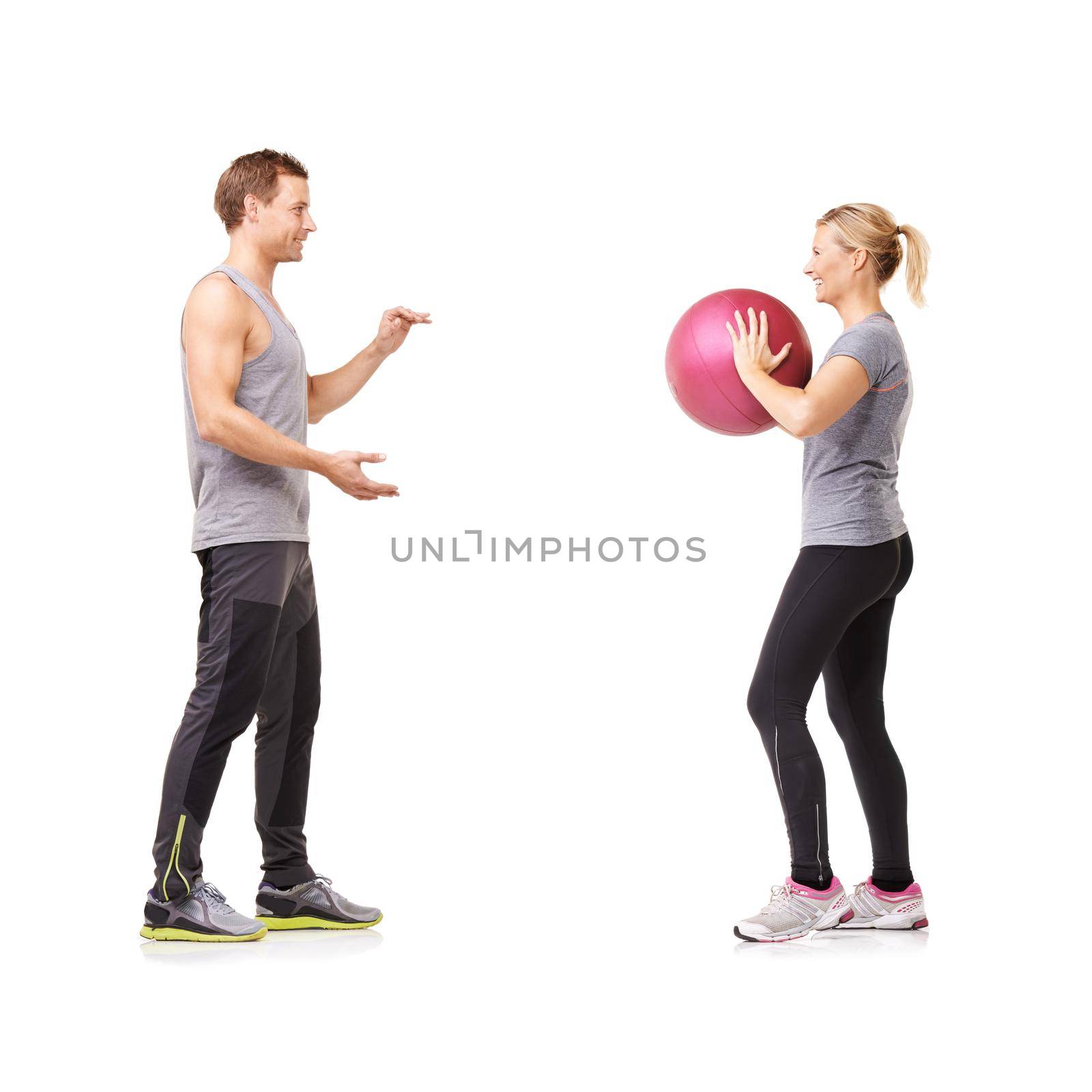 Fitness and friendship. A man and woman exercising by throwing a medicine ball to each other. by YuriArcurs