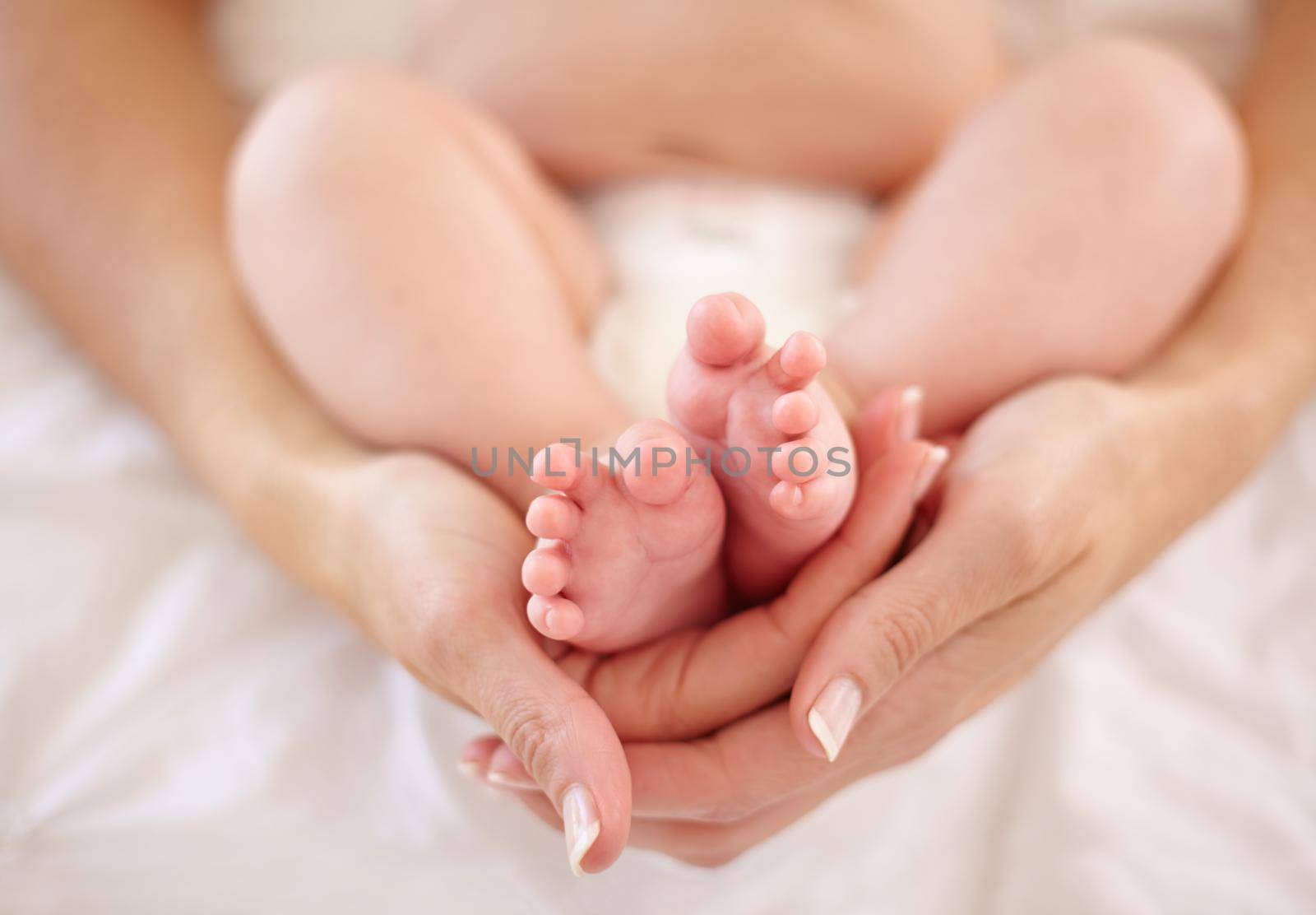 Wrapped in the arms of motherly love...Cropped image of a mother holding her babys feet. by YuriArcurs