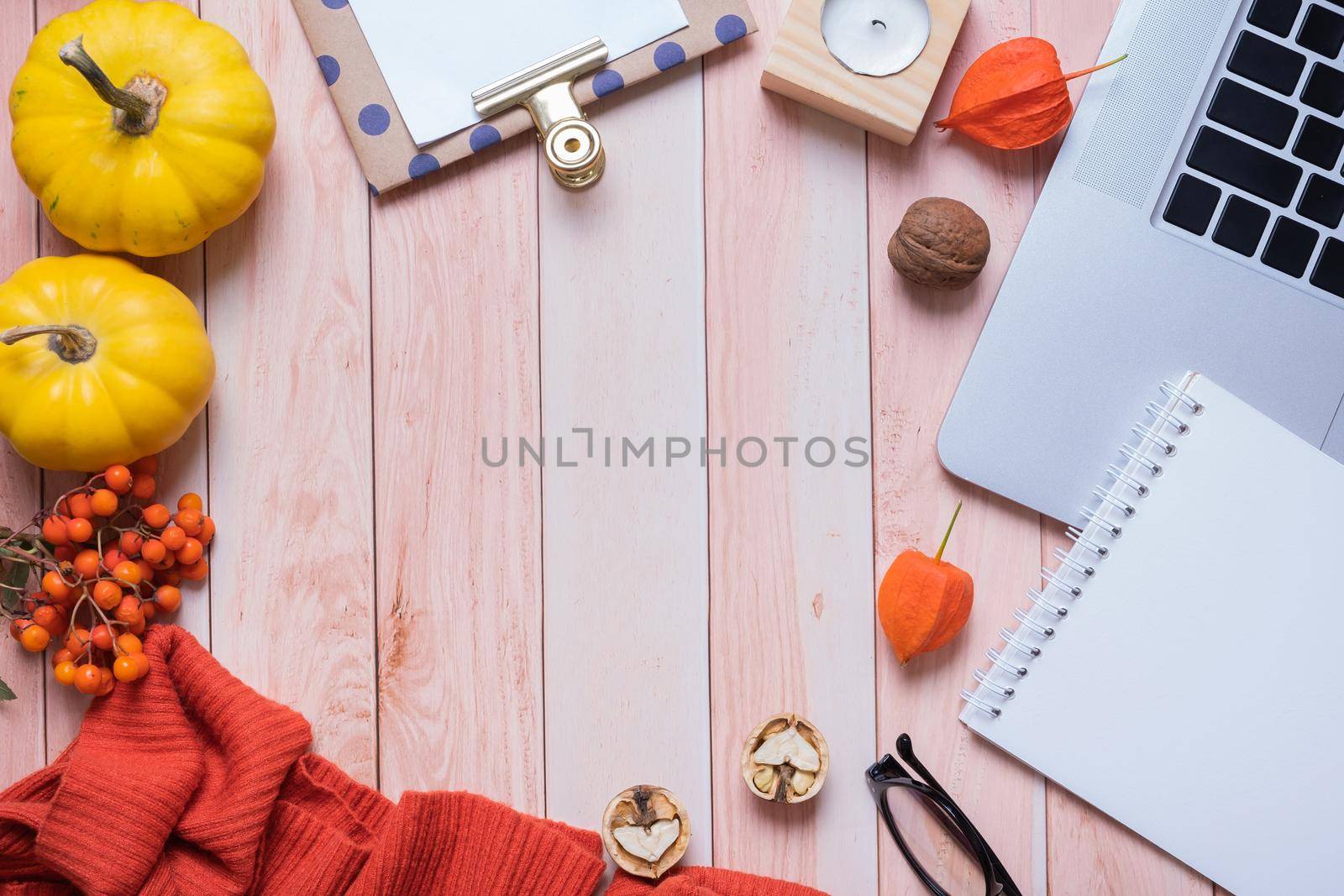 Frame made from note pad, laptop, sweater and pumpkins on wooden background. Autumn cozy decor top view. Copy space.
