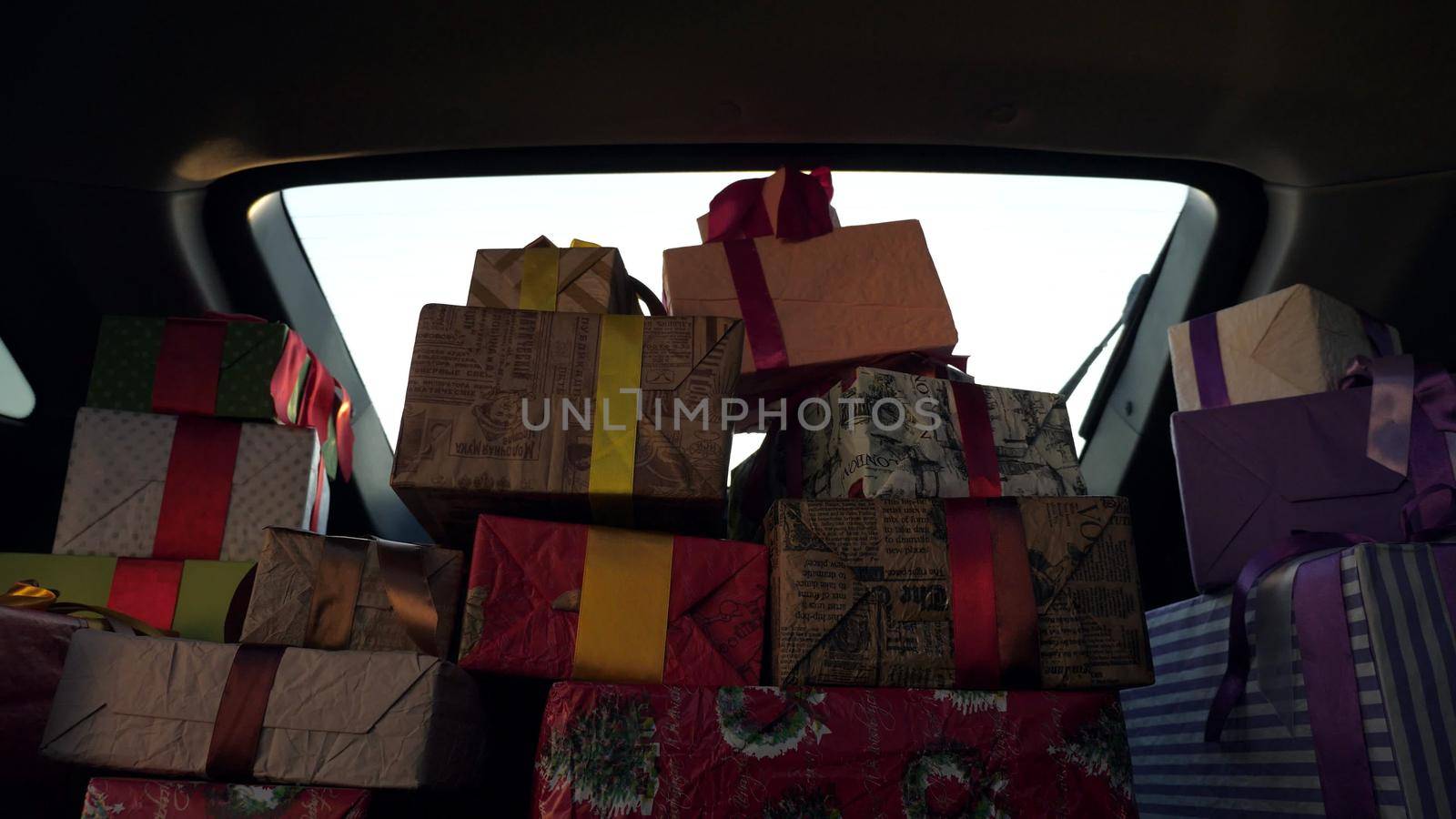 santa claus delivering gifts. gifts from santa. delivery service. deliveryman unloads boxes. gift boxes in car. beautifully wrapped parcels. view from inside the car. donation, charity or delivery concept. High quality photo