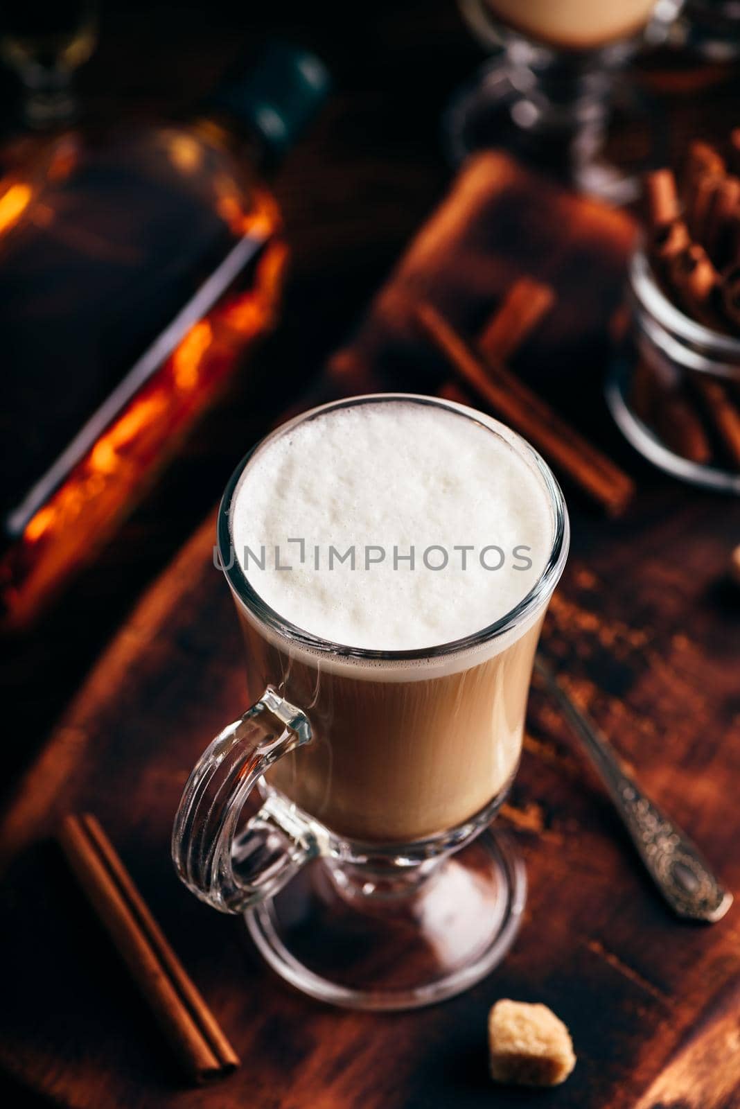 Coffee with Irish whiskey and whipped cream in glass on rustic wooden surface