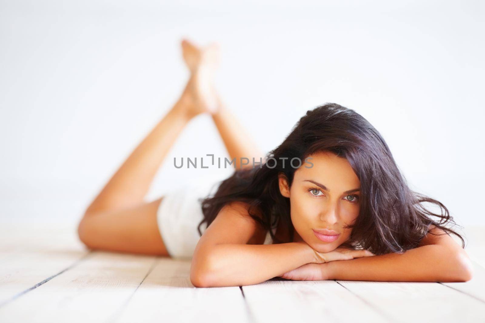 Portrait of sensuality. Studio portrait of a brunette woman lying on a wooden floor. by YuriArcurs