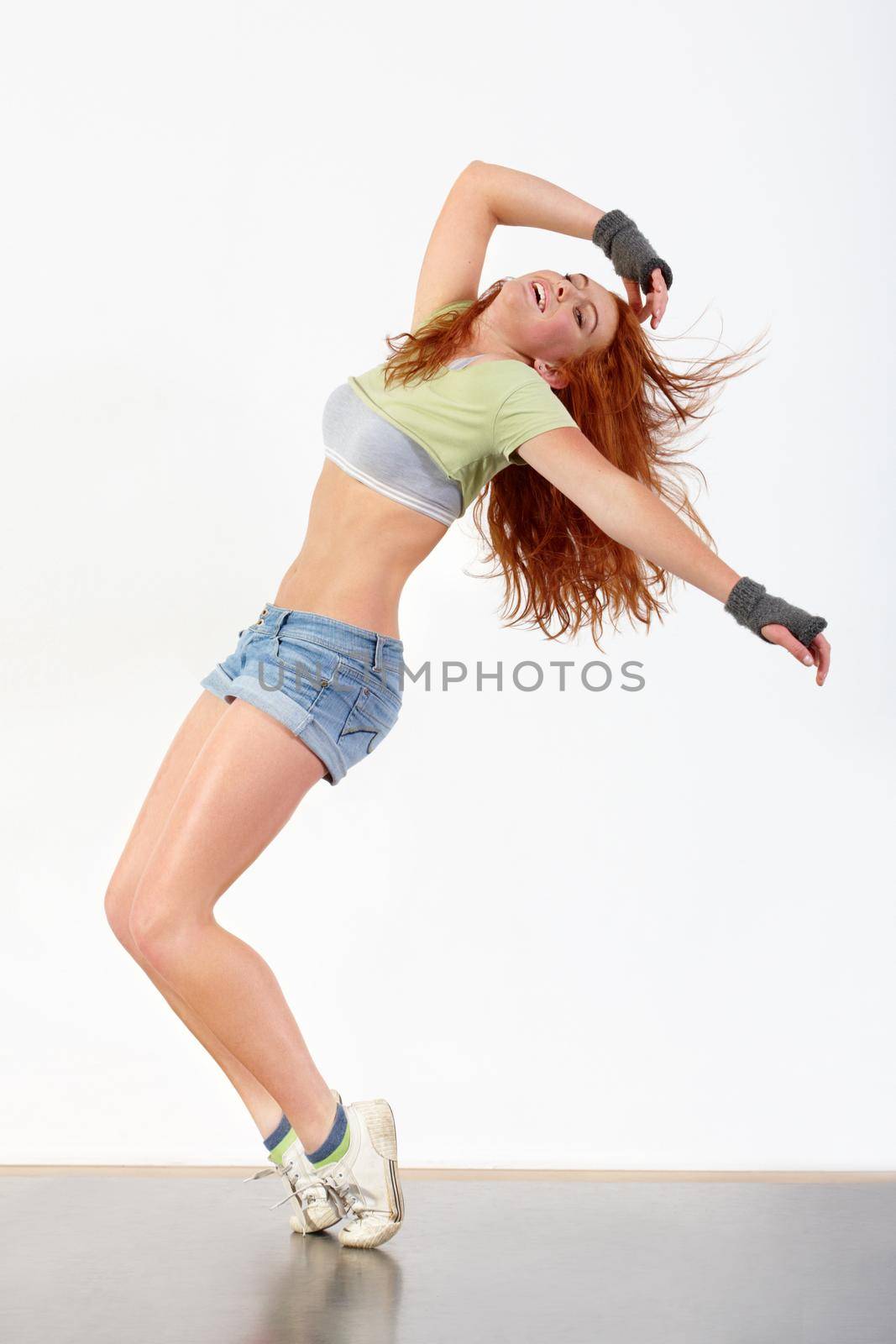 Feeling the beat. Young woman dancing against a white background. by YuriArcurs