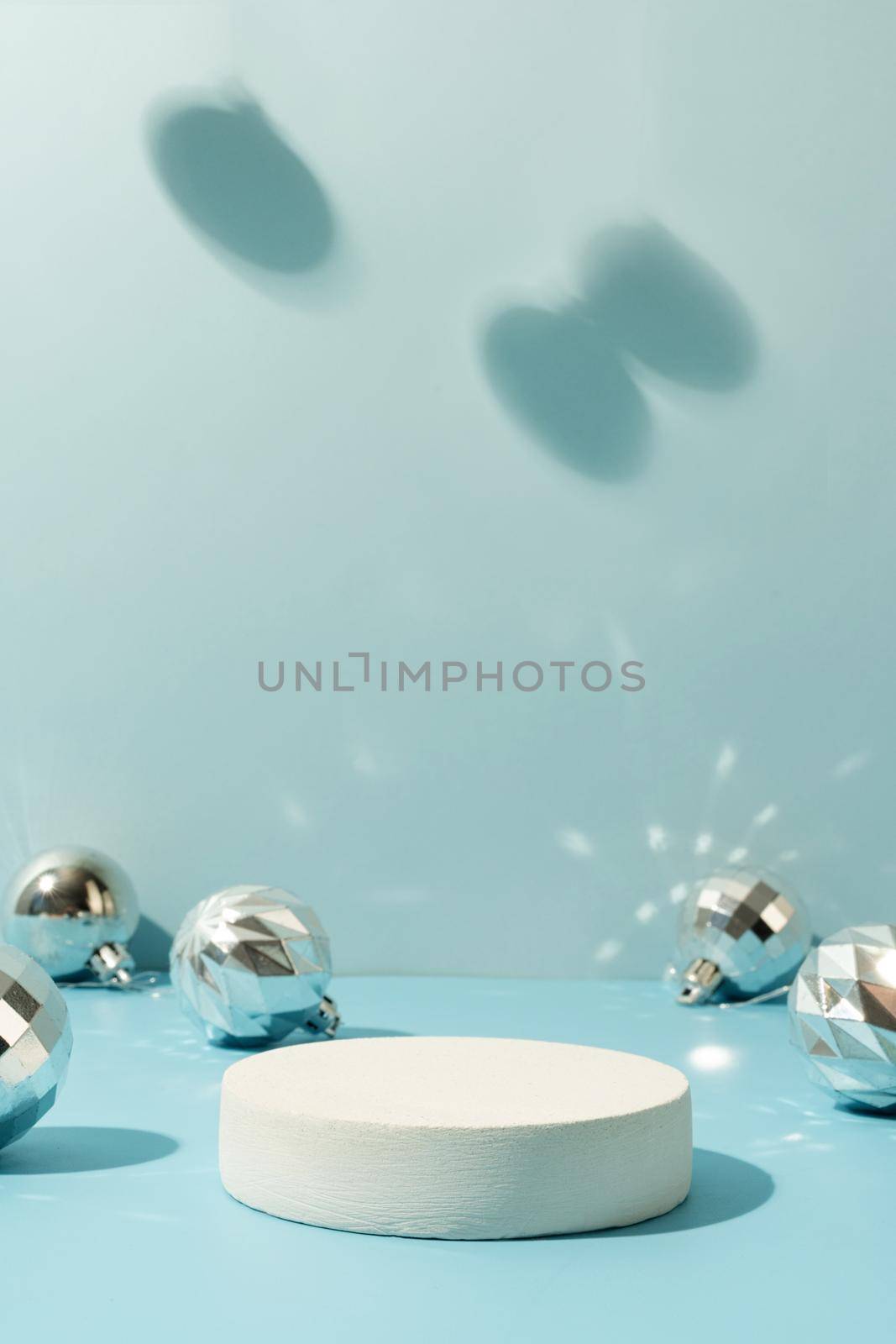 A minimalistic scene of a podium with christmas decorative balls on a light blue background by Desperada