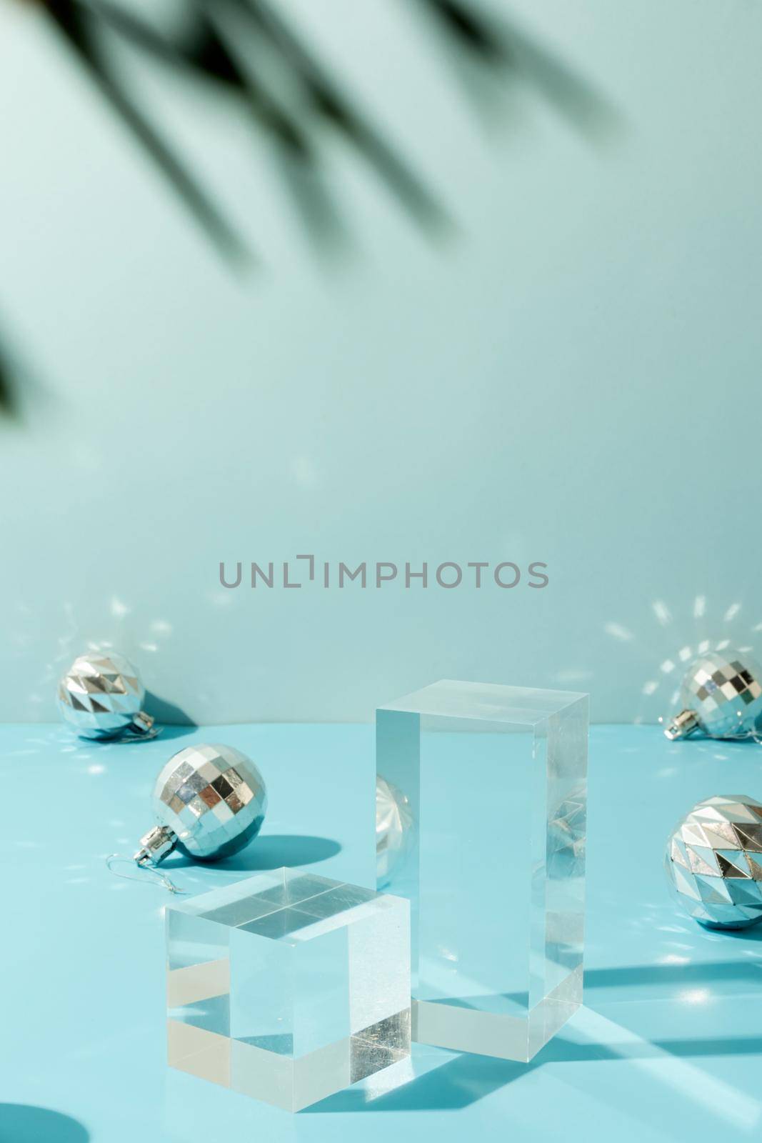 A minimalistic scene of glass podium with christmas decorative balls and pine tree on a light blue background. Catwalk for the presentation of products and cosmetics. Showcase with a stage for products, mockup design, seasonal