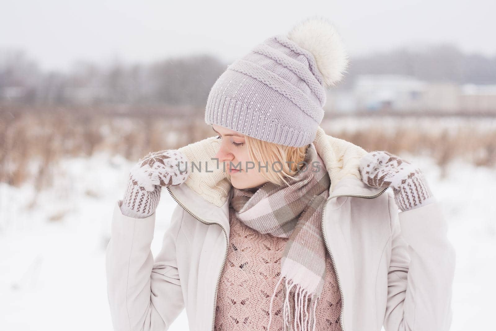 A blonde girl in winter clothes, walking on a snowy steppe. Smiling woman in light clothes in winter in the snow by Annu1tochka