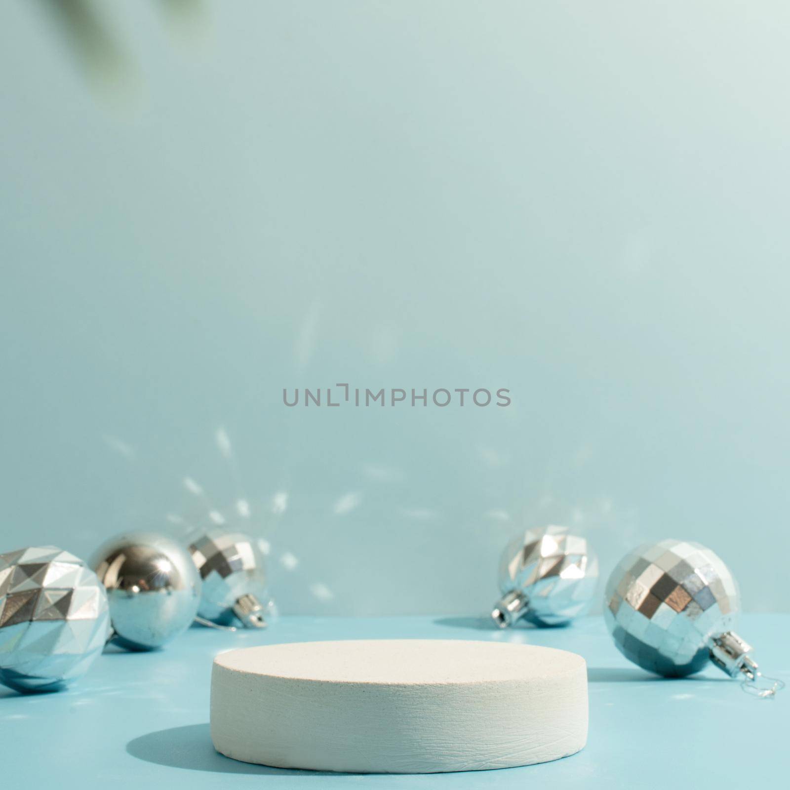 A minimalistic scene of a podium with christmas decorative balls and pine tree on a light blue background. Catwalk for the presentation of products and cosmetics. Showcase with a stage for products, mockup design, seasonal
