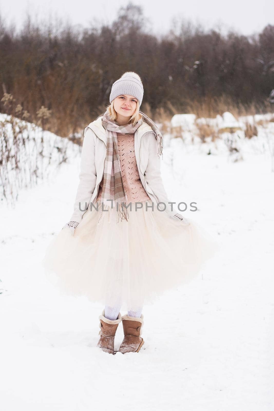 A blonde girl in winter clothes, walking on a snowy steppe. Smiling woman in light clothes in winter in the snow by Annu1tochka