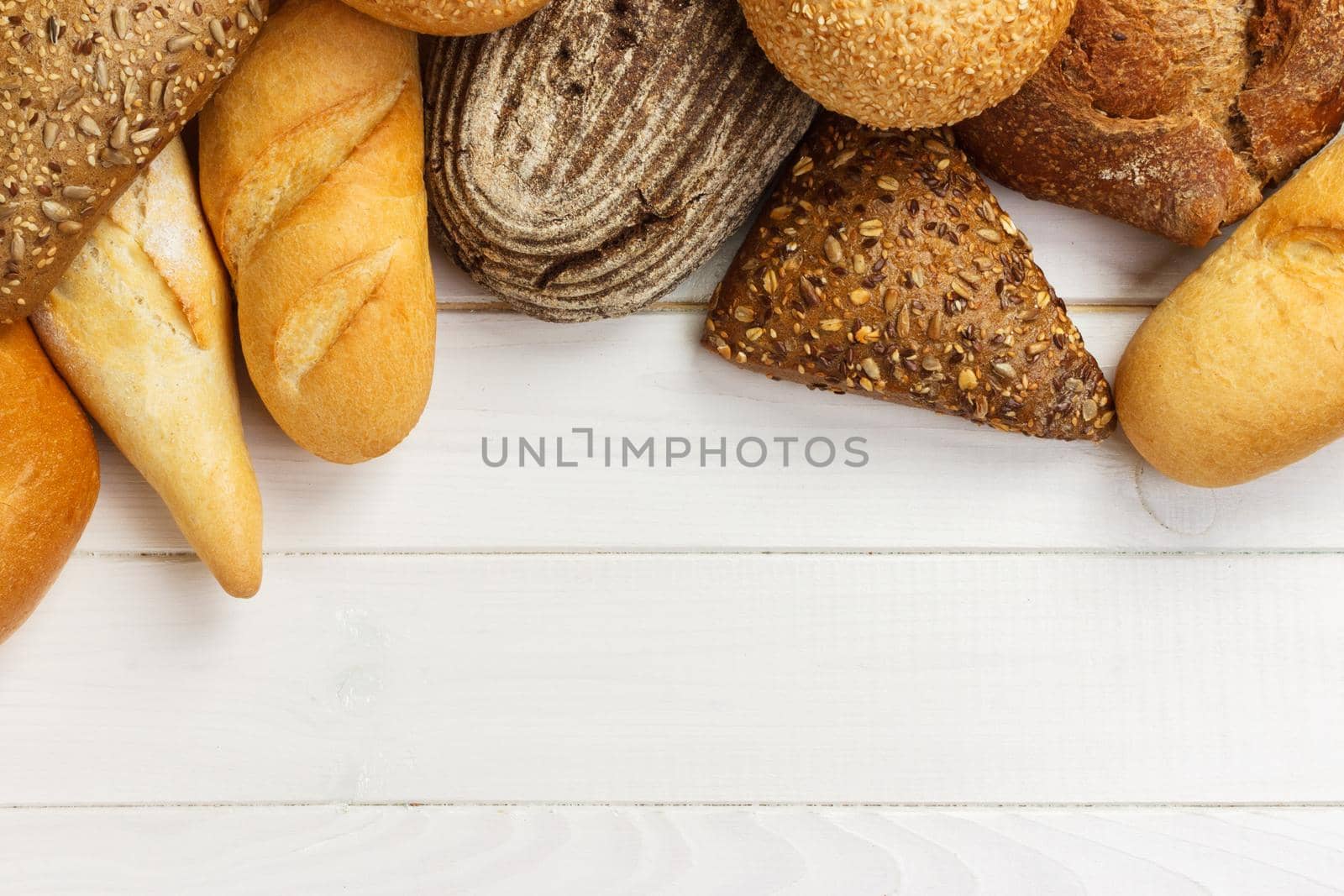 Assortment of baked bread on white wooden table background. top view with copy space.