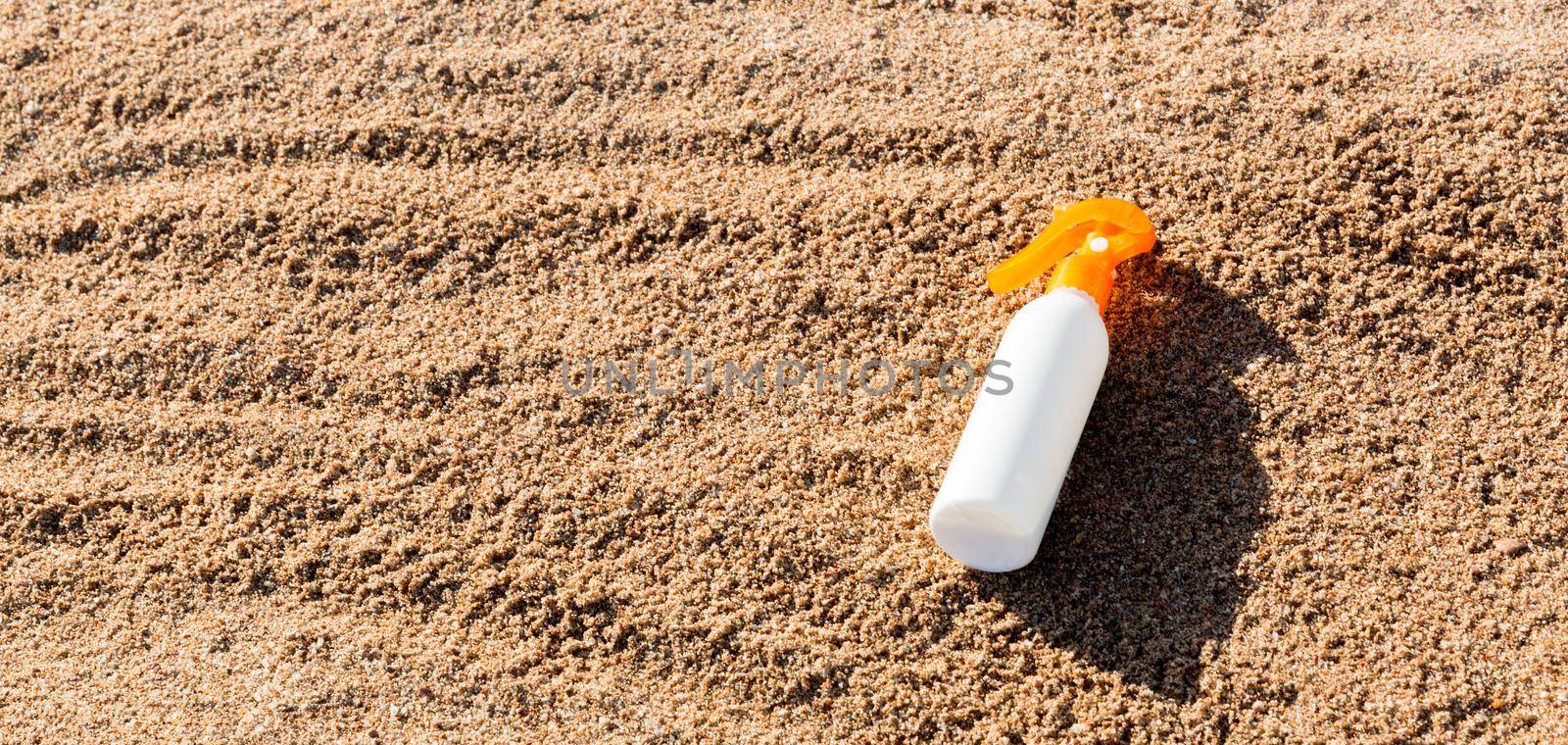 Suntan lotion white bottle on sand with copy space. sunblock spf cream on the sea beach in summer vacation concept.