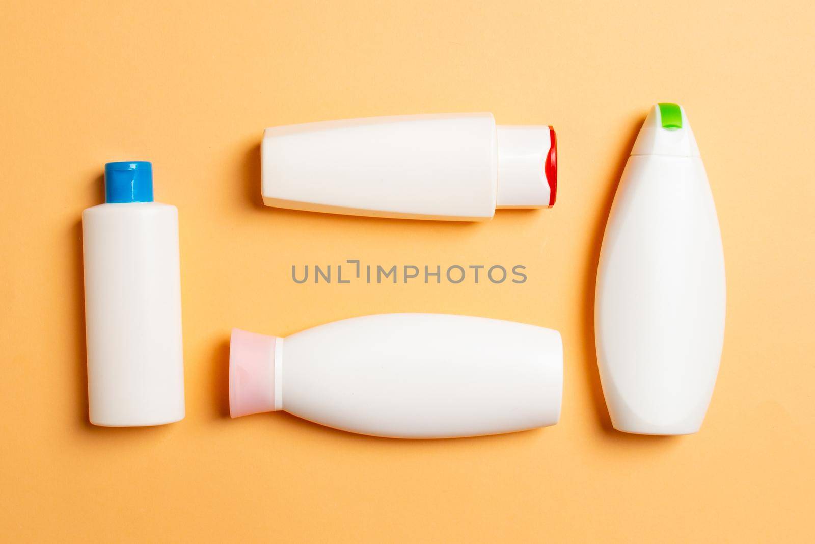 Set of White Cosmetic containers isolated on colored background, top view with copy space. Group of plastic bodycare bottle containers with empty space for you design.