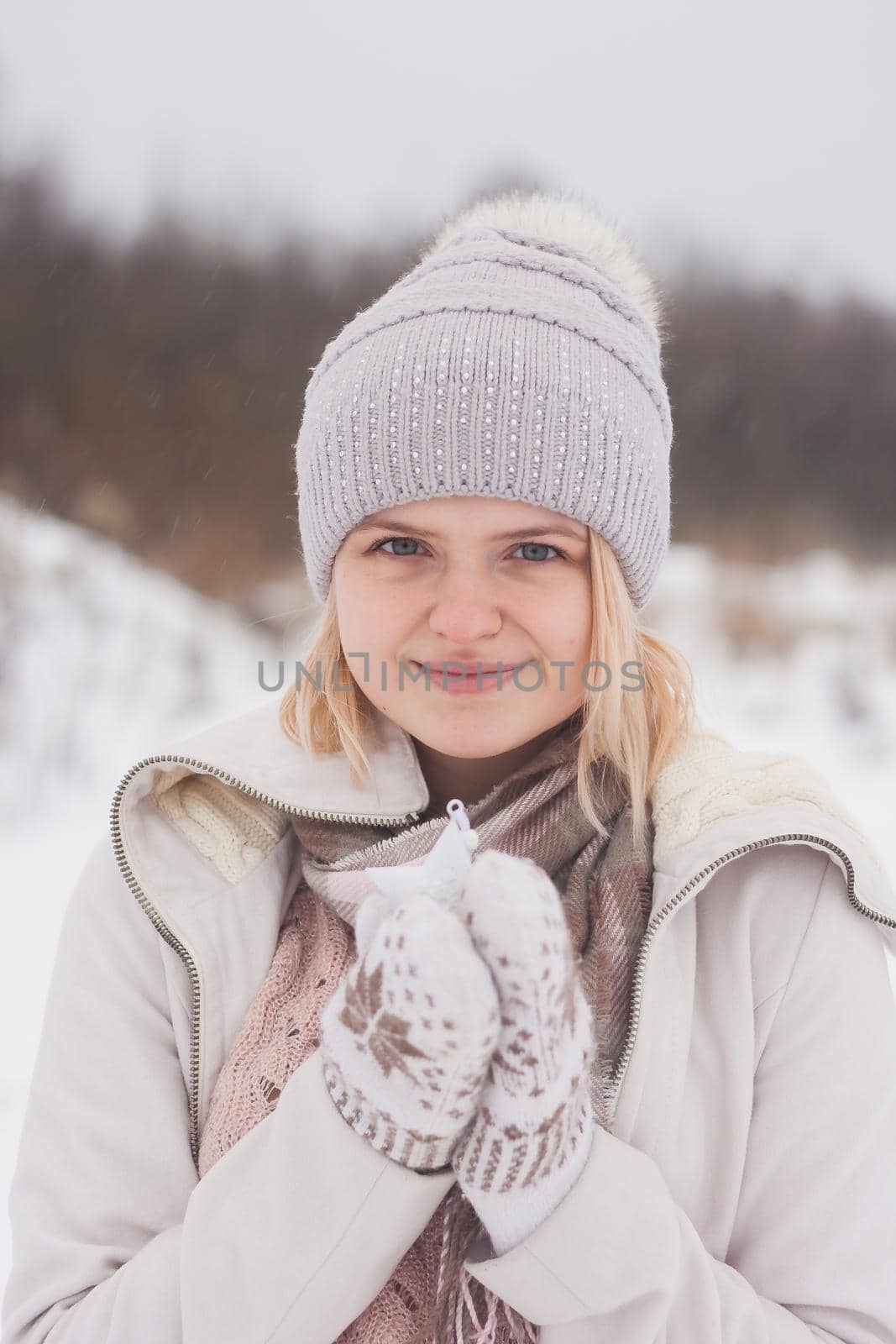A blonde girl in winter clothes, walking on a snowy steppe. Smiling woman in light clothes in winter in the snow.