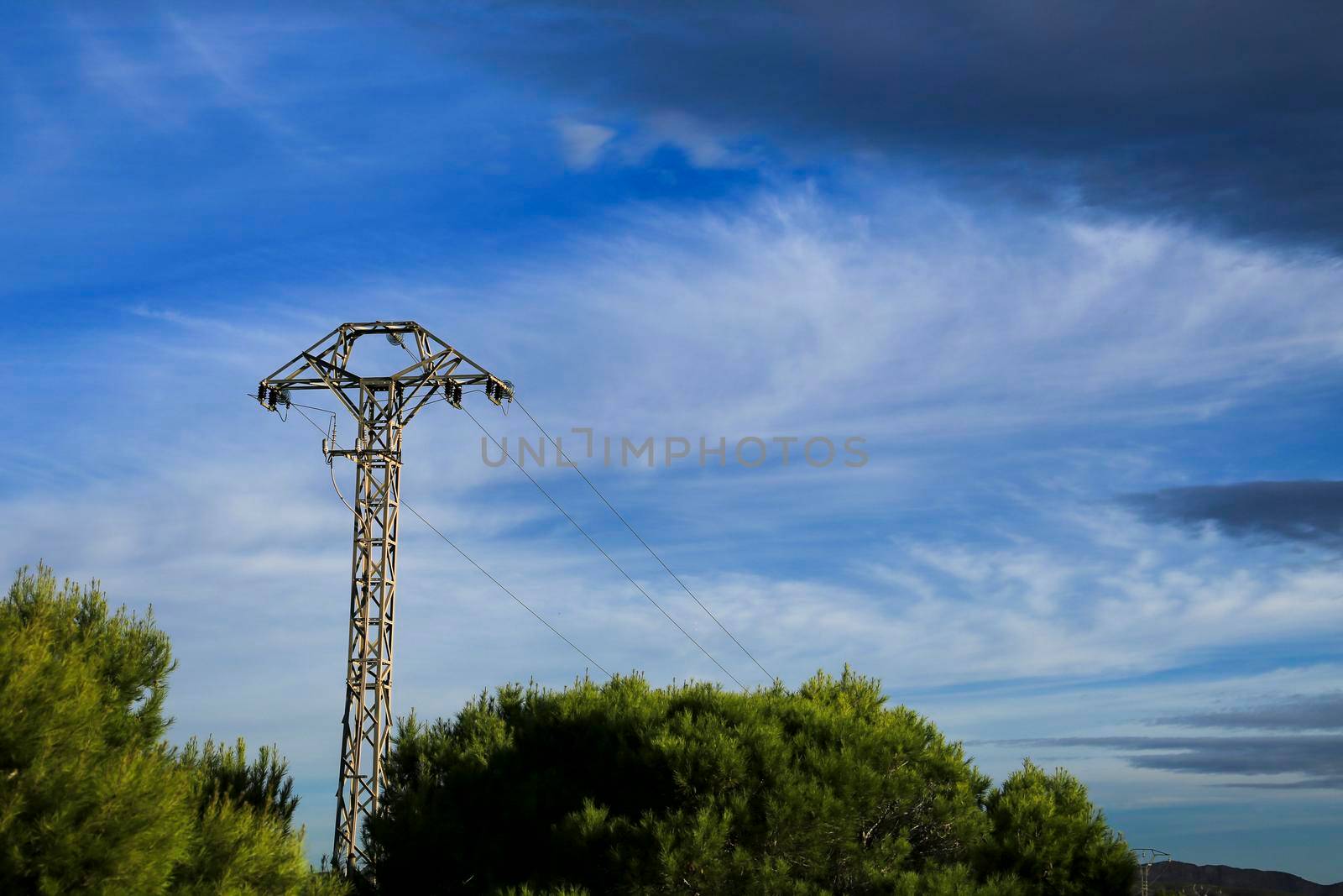 Power lines tower under blue sky in the countryside in Spain