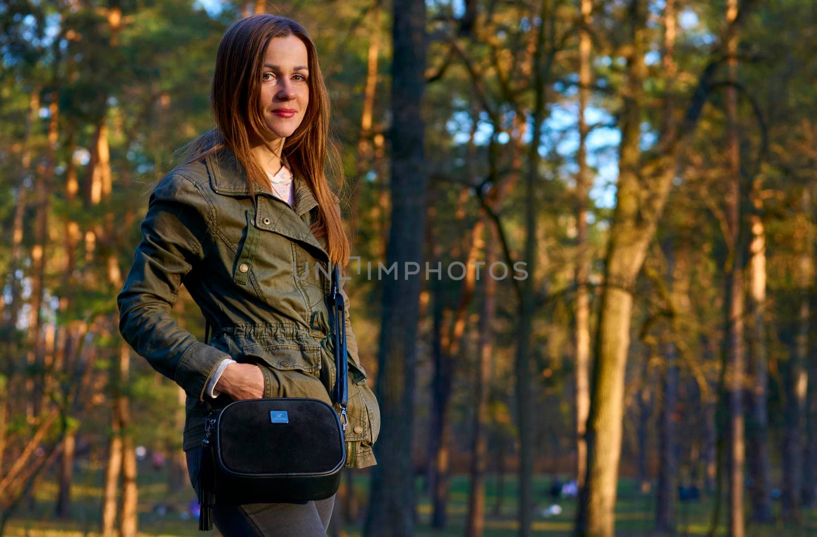 an adult female human being. Pretty young woman in a green jacket in autumn park with pine