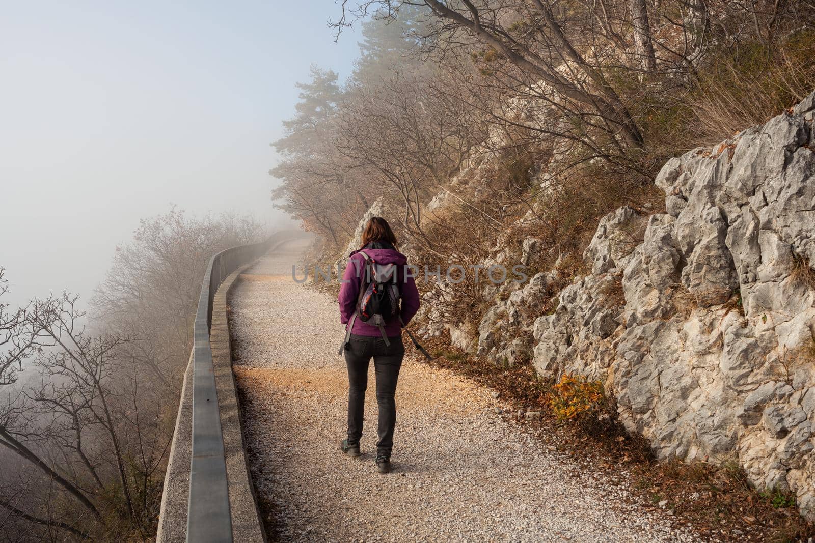 Back view of a Woman walking alone on rural misty path called Napoleonica, Trieste
