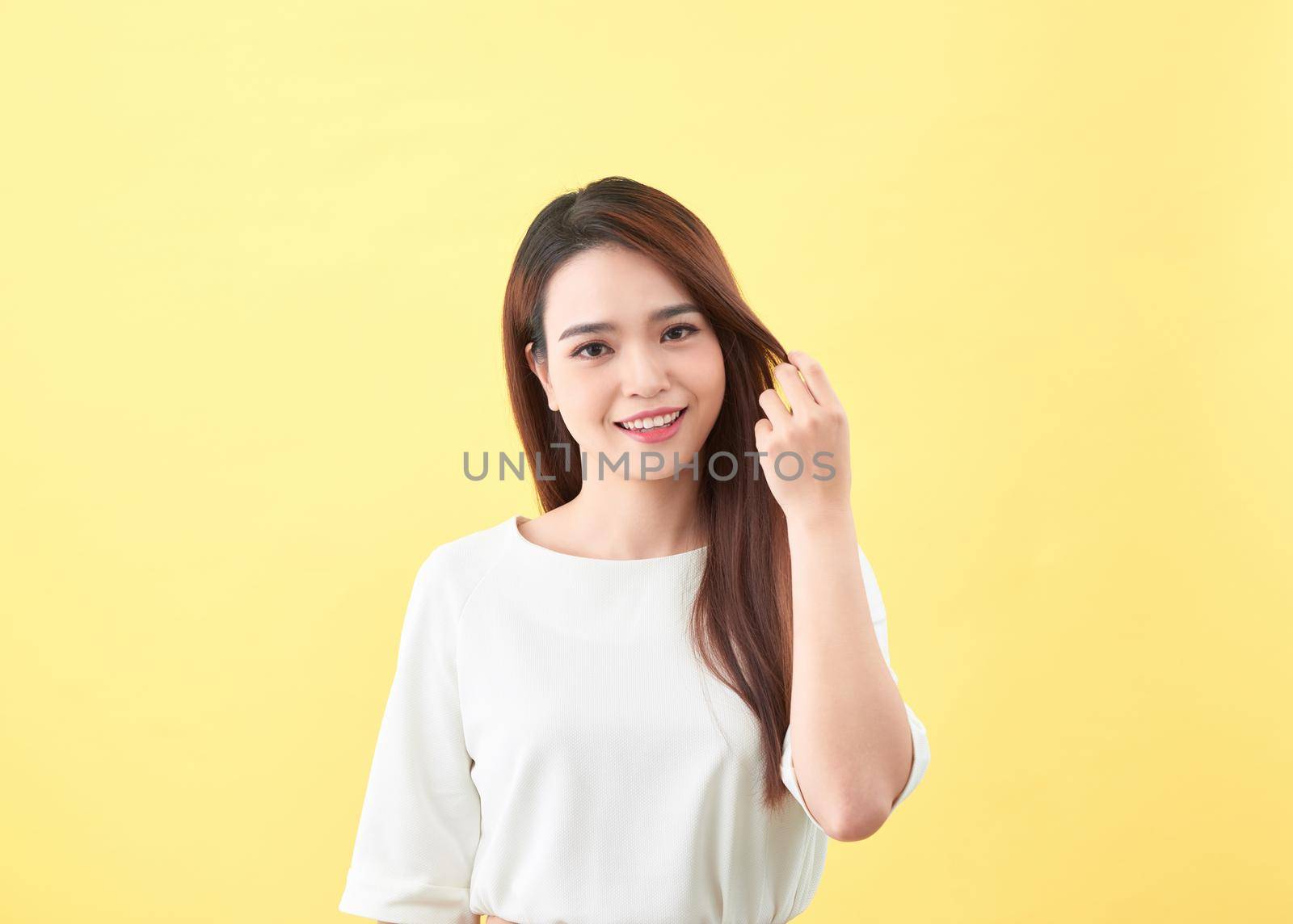 Beauty woman touch her long hair isolated on yellow background, asian beauty 